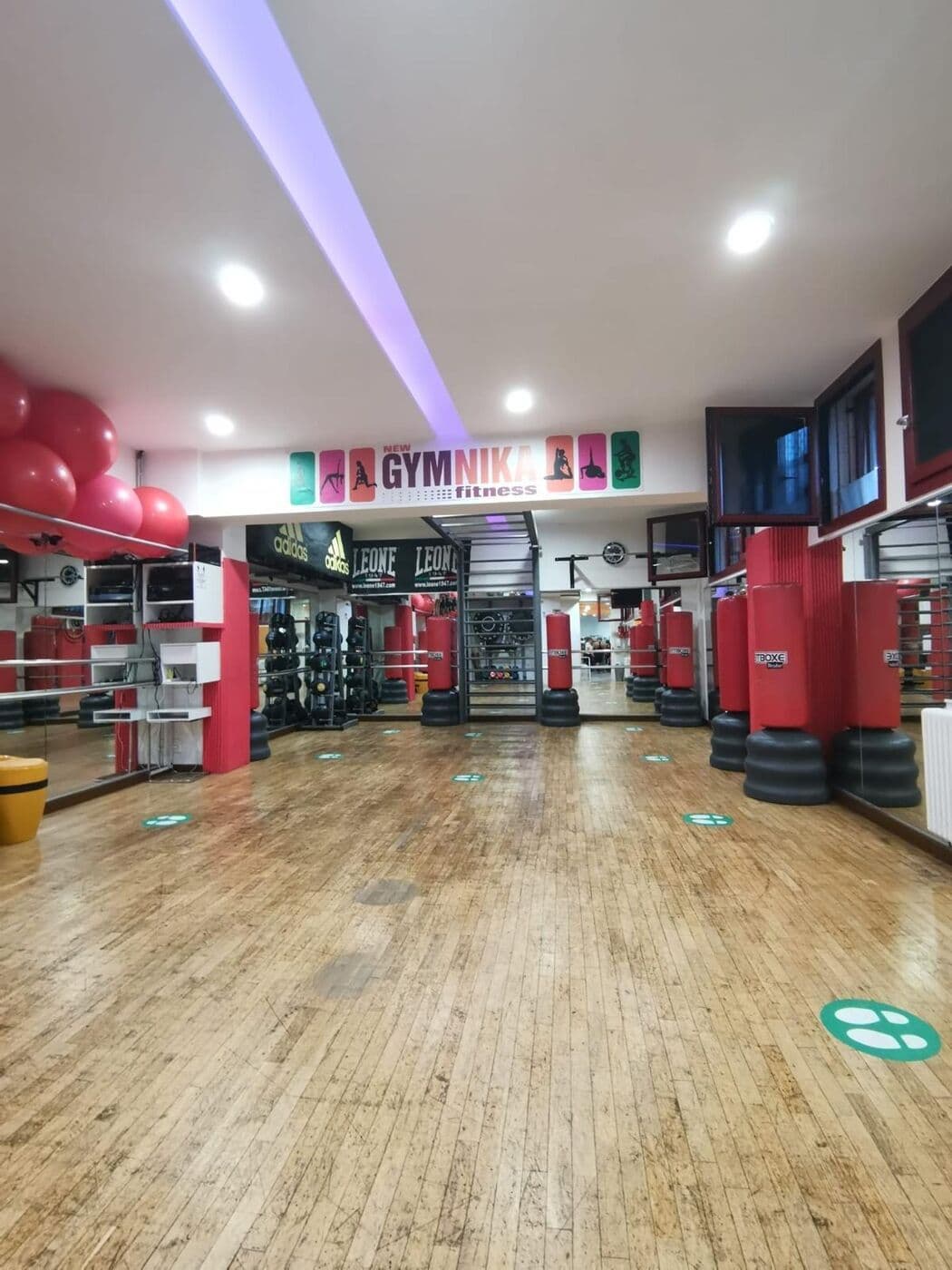 Sala corsi con parquet, sacchi da boxe rossi, spalliera e fitball